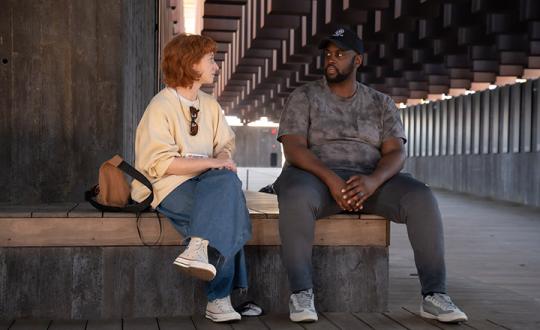 Two people having a casual conversation sit on a bench inside the National Memorial for Peace and Justice in Montgomery, Alabama.