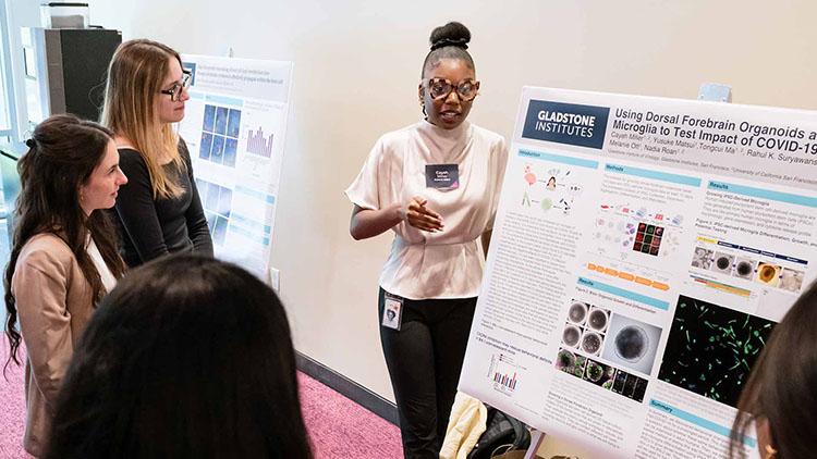 A PUMAS internship participant presents their research poster to event attendees.